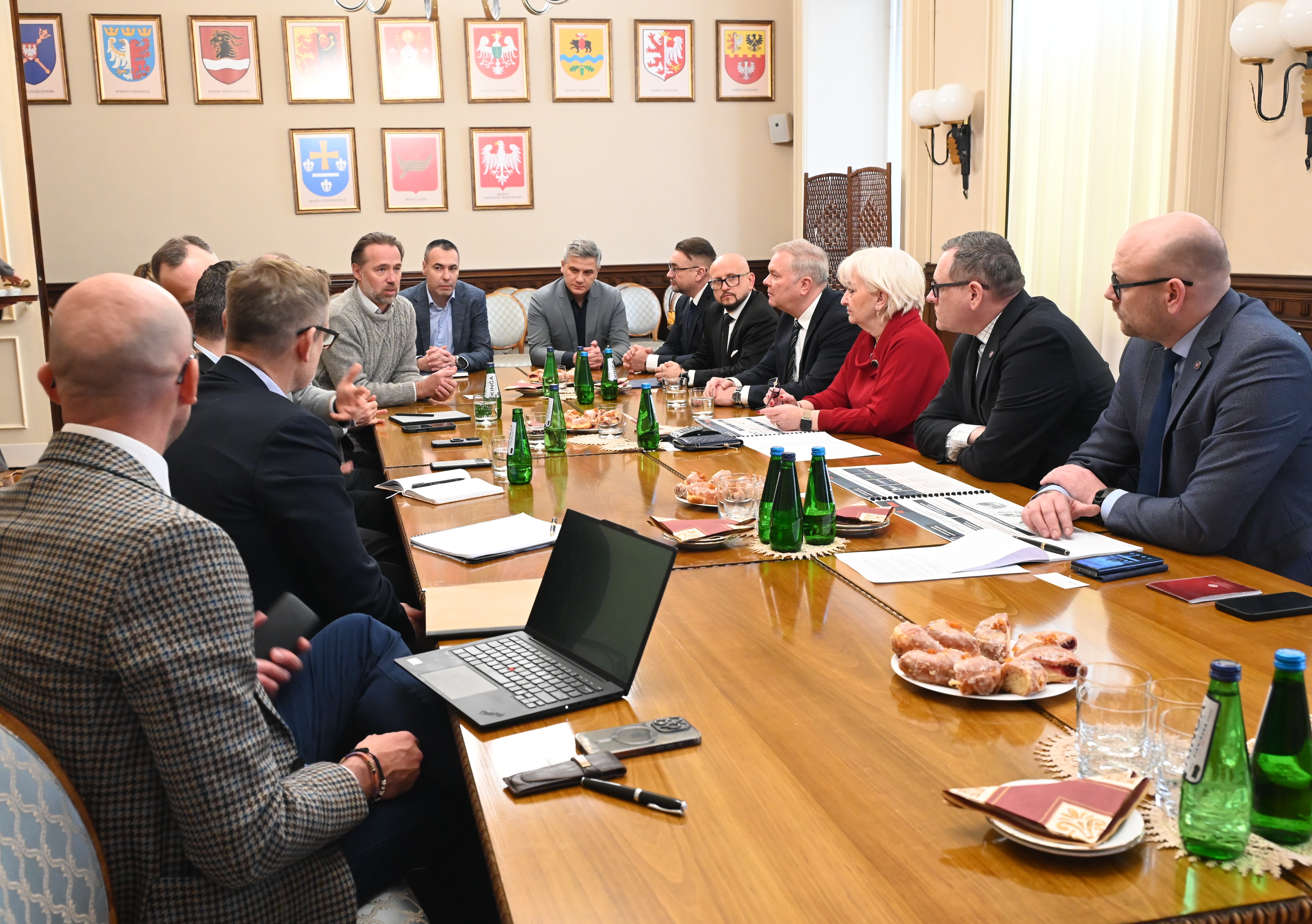 mężczyźni i&nbsp;kobiety siedzą przy stole w&nbsp;sali Ł&oacute;dzkiego Urzędu Wojew&oacute;dzkiego