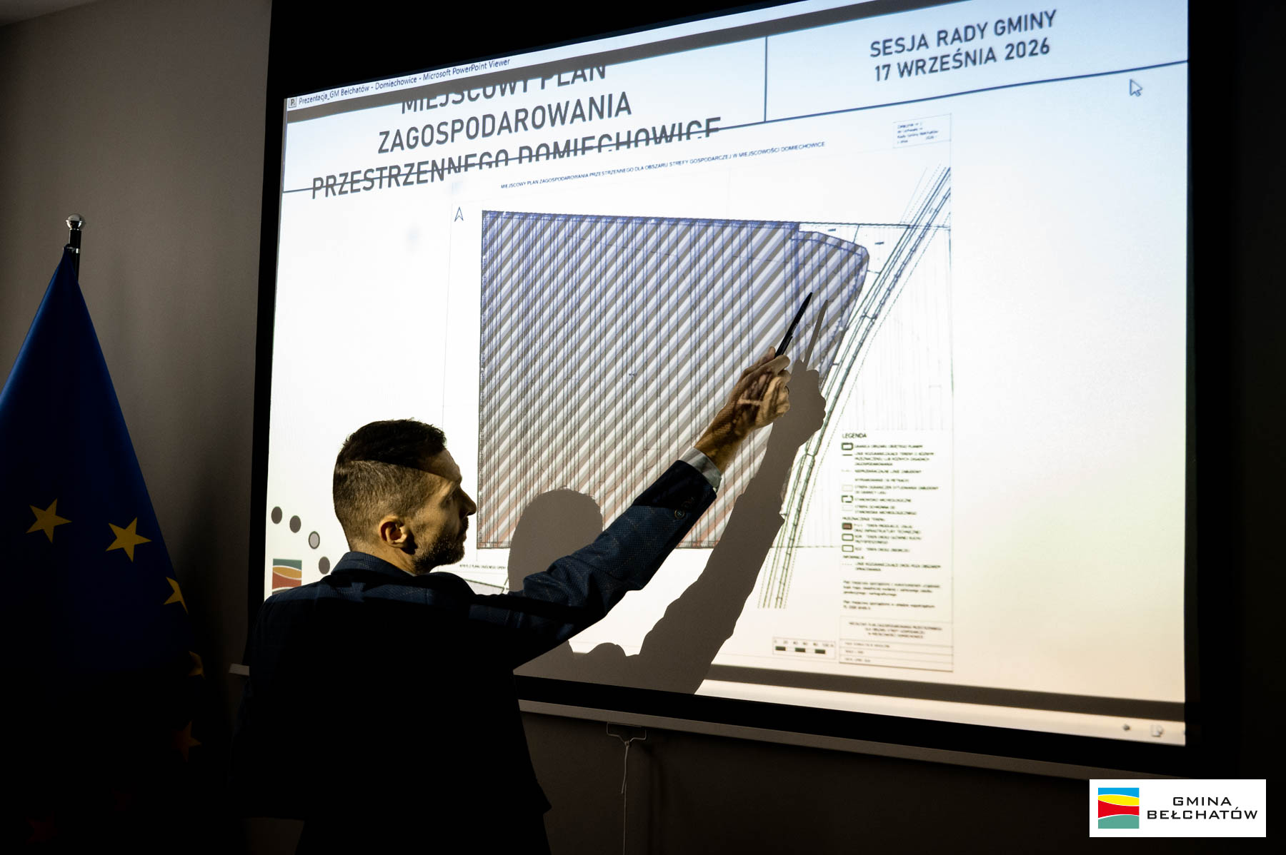 mężczyzna przy planszy pokazuje wskaźnikiem, na&nbsp;planszy napis miejscowy plan zagospodarowania przestrzennego