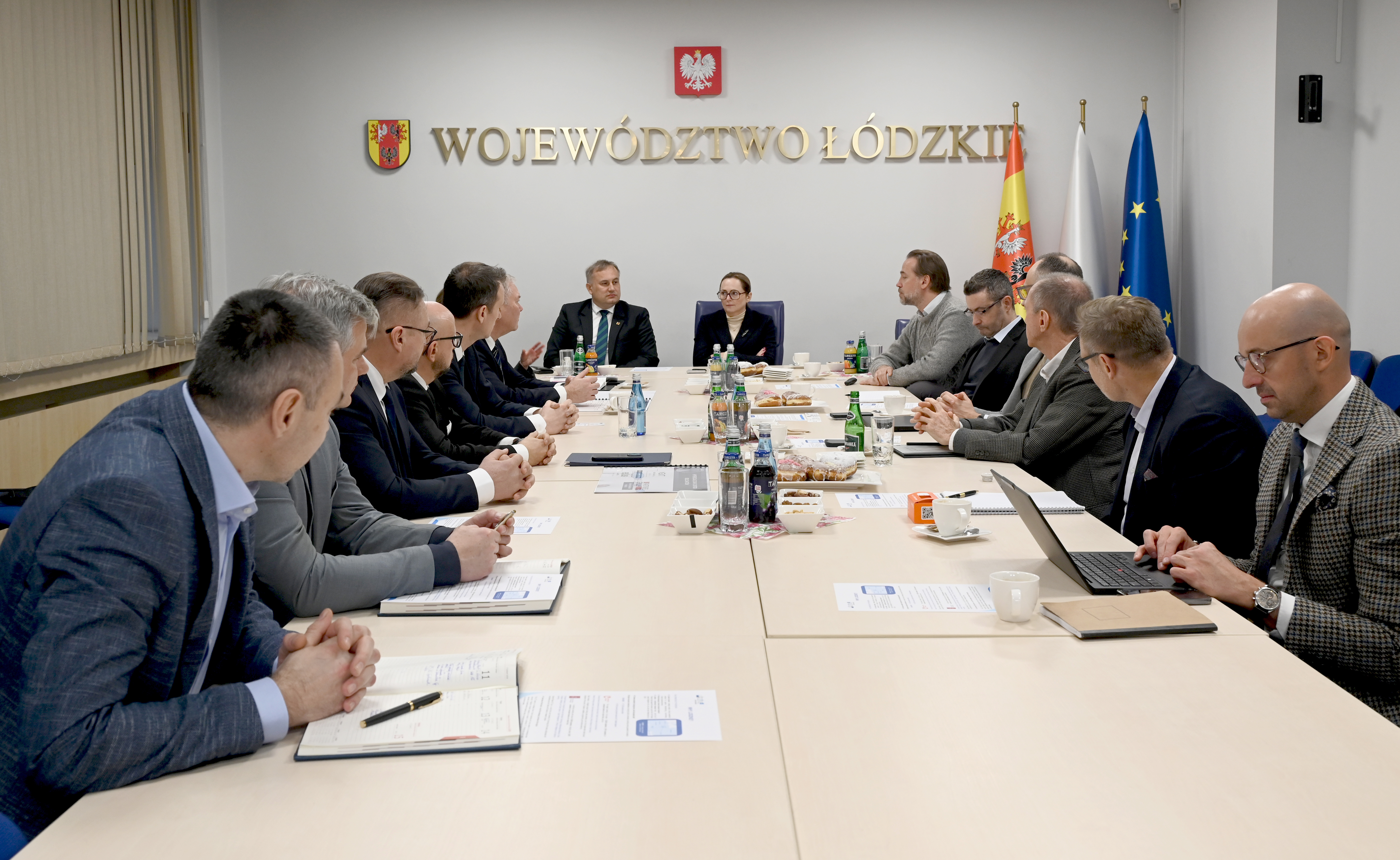 kobiety i&nbsp;mężczyźni siedzą przy stole konferencyjnym w&nbsp;sali Urzędu Marszałkowskiego w&nbsp;Ł&oacute;dzi