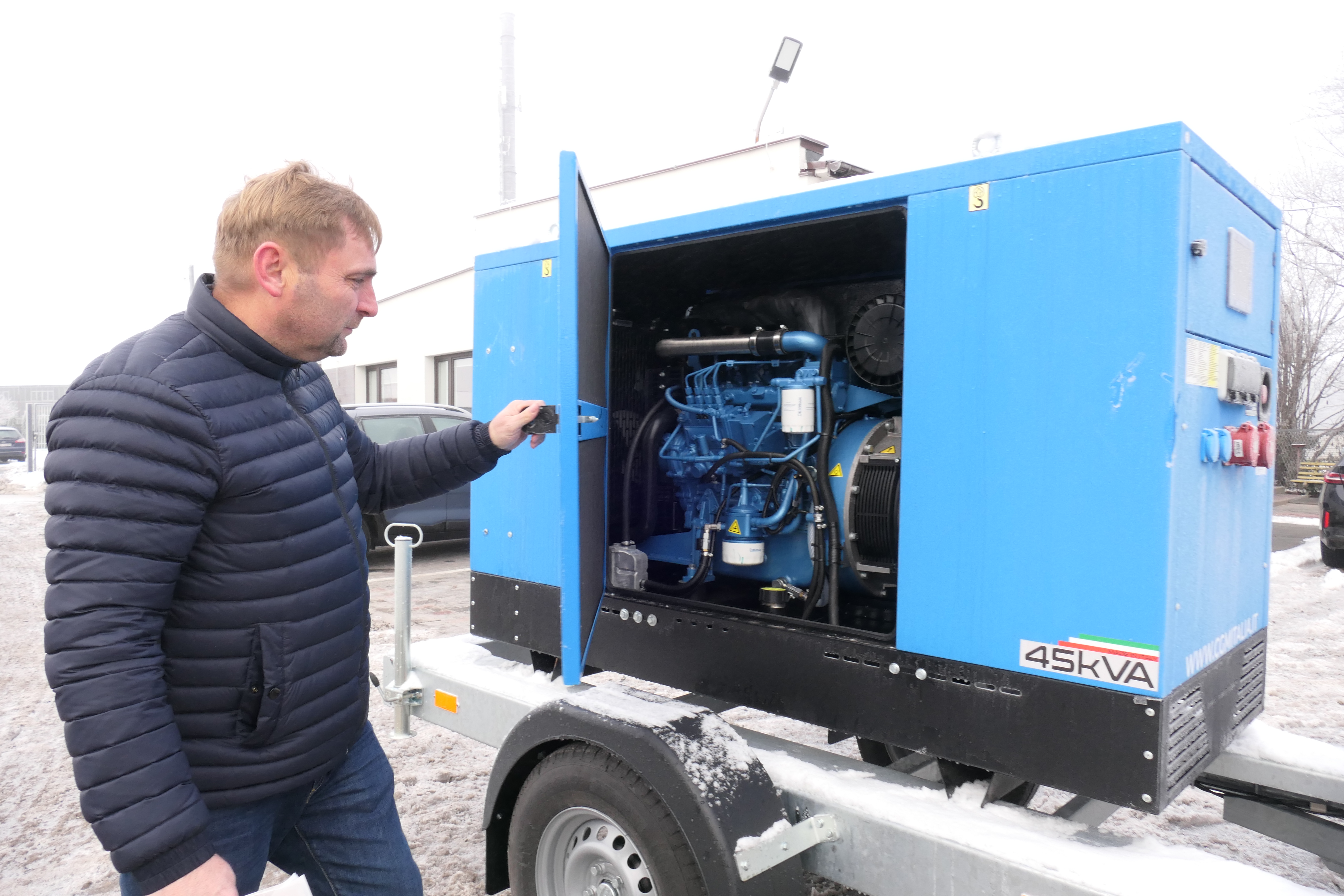 mężczyzna stoi przy agregacie prądotw&oacute;rczym 