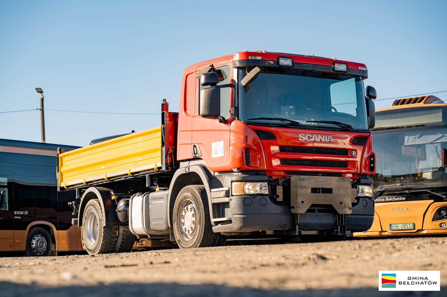 samoch&oacute;d ciężarowy marki scania, w&nbsp;tle stojące autobusy