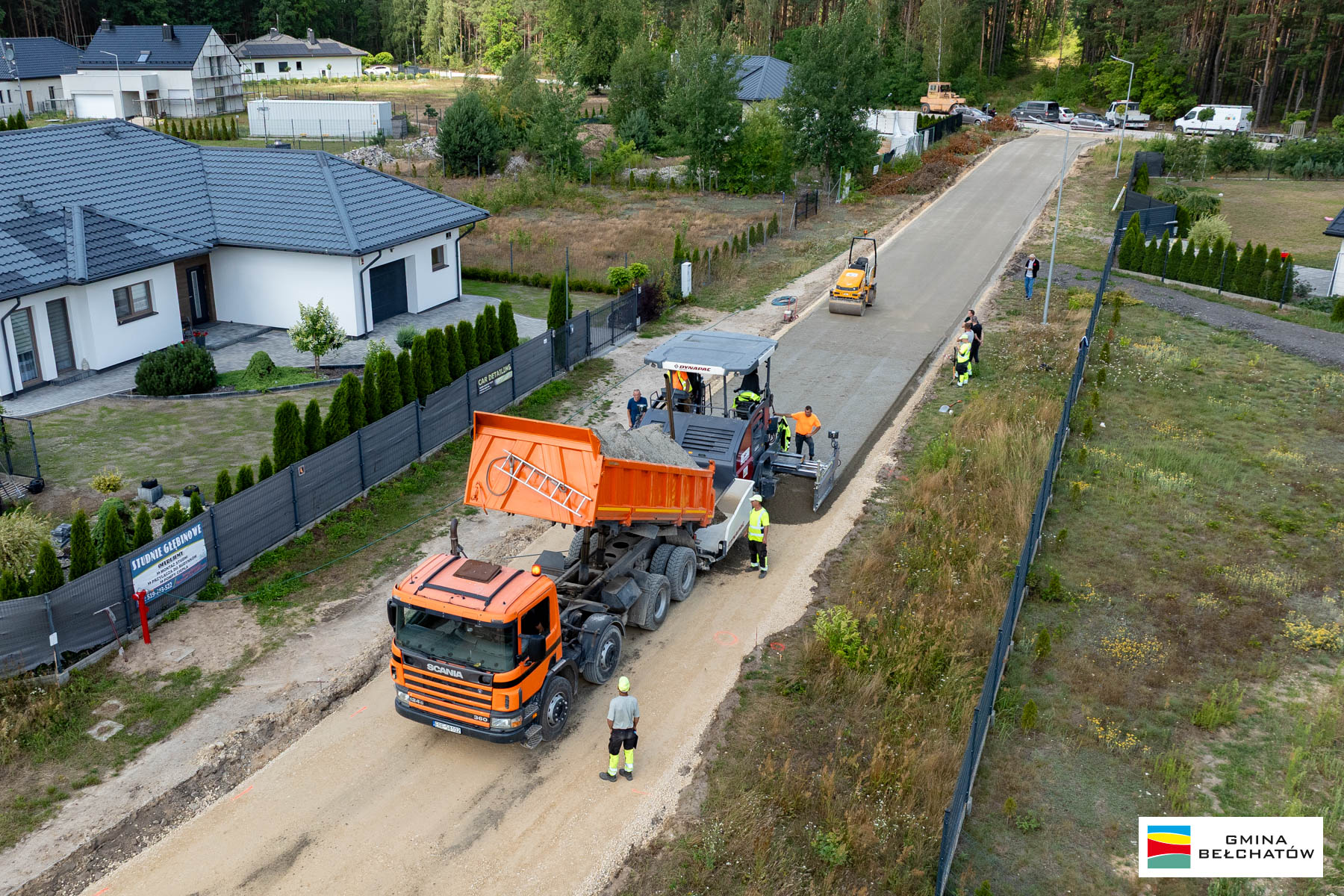 widok z&nbsp;lotu ptaka na&nbsp;osiedlową uliczkę, maszyny budowlane rozkładają betonową nawierzchnię
