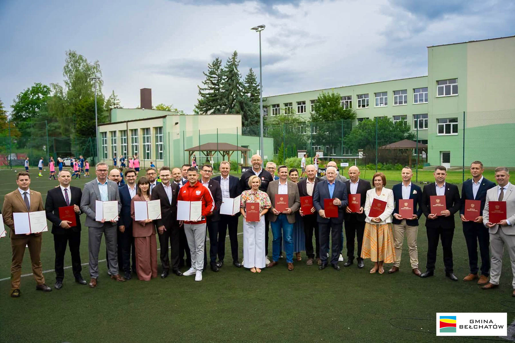grupa kobiet i&nbsp;mężczyzn stoi na&nbsp;boisku