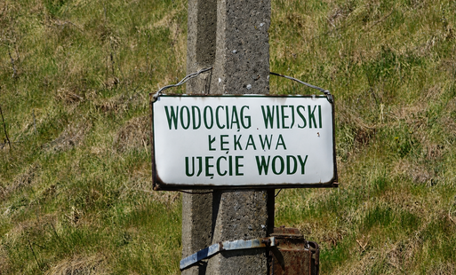 tabliczka na słupie z napisem wodociąg wiejski łękawa ujęcie wody