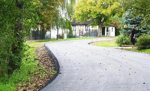 asfaltowa droga w Józefowie, nowa, równa nawierzchnia, wijąca się przez miescowość, na poboczach zieleń