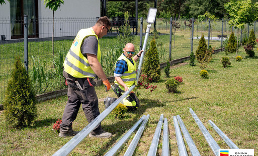 pracownicy gminnej spółki komunalnej w mazwurach montuja słupy oświetleniowe